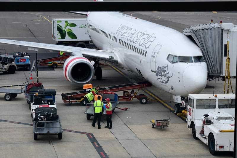 Ground crew are seen lading baggage onto a Virgin Australia plane