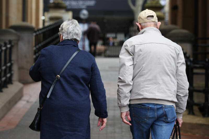 2 Elderly people walk down a street in Sydney,
