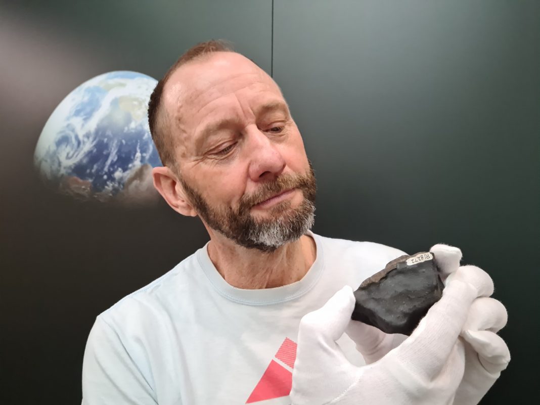 62-year-old male geologist wearing white gloves to hold a meteorite fragment