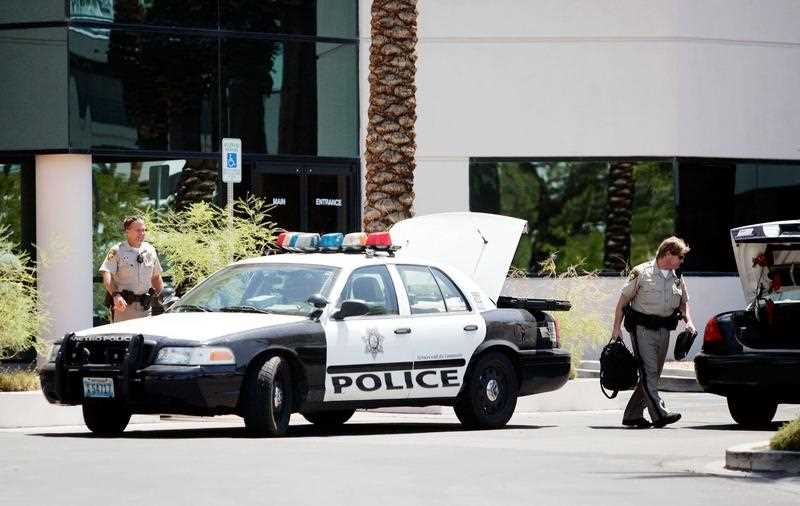 A Las Vegas police officer transfers equipment from one car to another