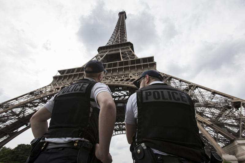French riot police officers patrol under the Eiffel Tower
