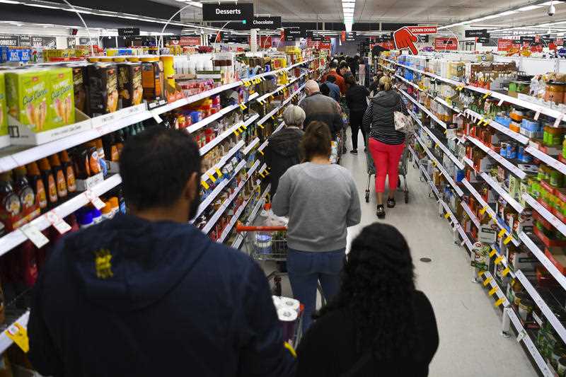 Customers stand in long lines at a check out counter at a supermarket
