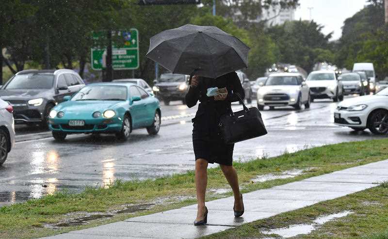 A woman under an umbrella is seen walking through Kangaroo Point as rain falls over Brisbane