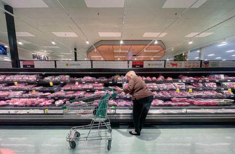A woman is seen shopping in the meat section at a Woolworths Supermarket