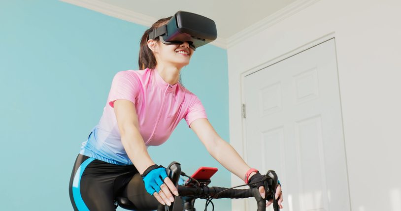 woman cycling with VR glasses in a room