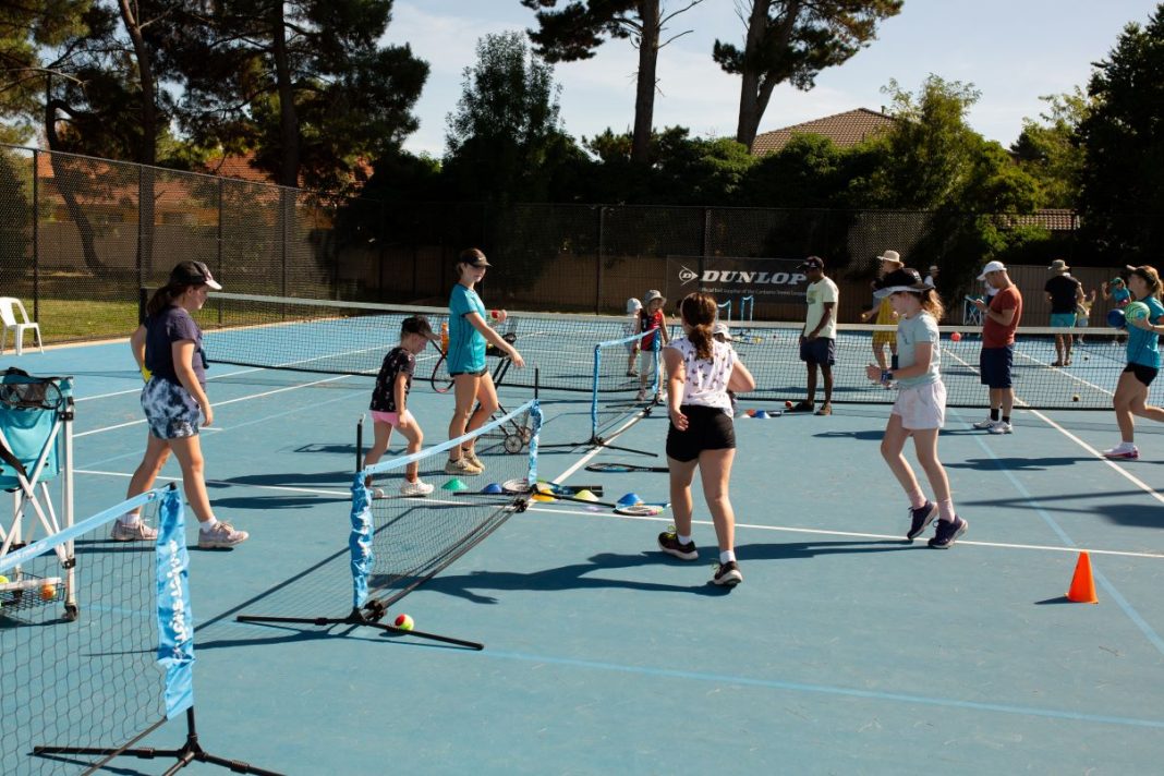 lots of girls and adults active on tennis courts