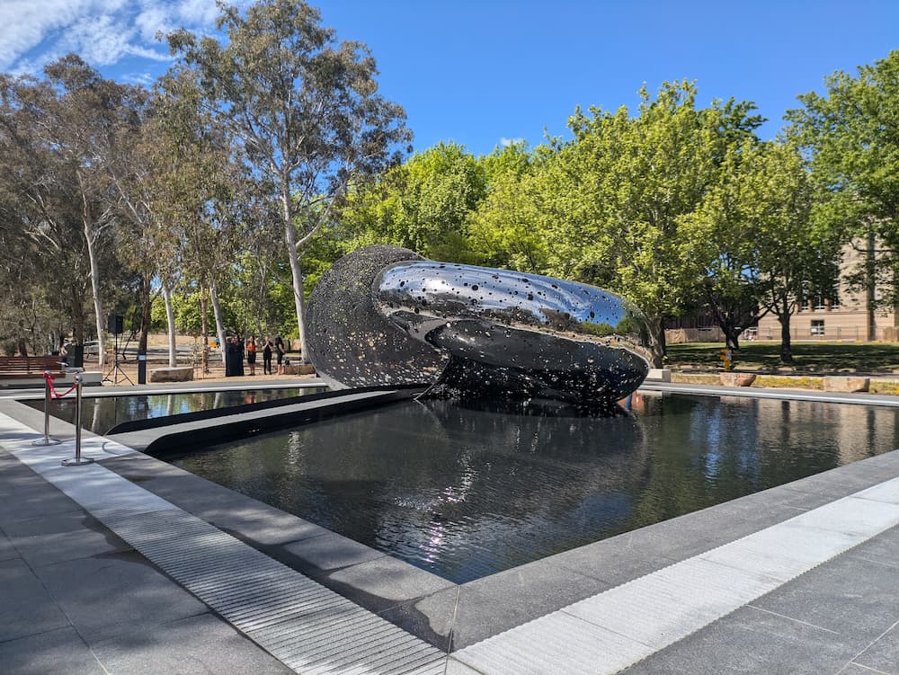 Lindy Lee’s Ouroboros sculpture levitates in a 240-square metre pond with a walkway guiding people into the “mouth” of the sculpture at the National Gallery of Australia. Picture: Lillian Altman