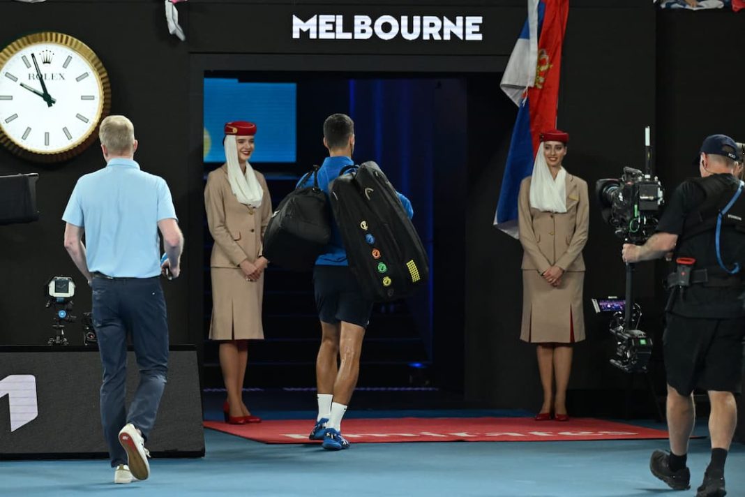 Novak Djokovic leaves court trailed by Jim Courier (left), who he refused to be interviewed by. (James Ross/AAP PHOTOS)